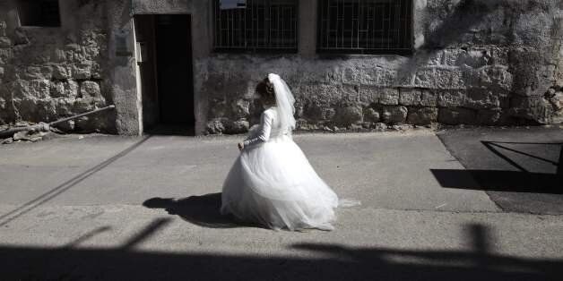 TOPSHOT - An ultra-Orthodox Jewish girl wearing a bride outfit walks in the street during a school Purim celebration four days ahead of the official holiday on the Jewish calendar in the ultra-Orthodox Jewish neighbourhood of Mea Shearim in Jerusalem on March 8, 2017.The carnival-like Purim holiday is celebrated with parades and costume parties to commemorate the deliverance of the Jewish people from a plot to exterminate them in the ancient Persian empire 2,500 years ago, as recorded in the Biblical Book of Esther. / AFP PHOTO / MENAHEM KAHANA (Photo credit should read MENAHEM KAHANA/AFP/Getty Images)