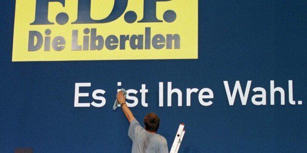 A worker gives a final touch to a poster for Germany's Free Democrats (FDP) with the slogan