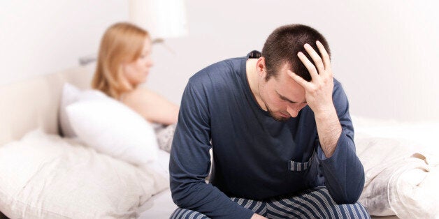 Upset man sitting on the bed with woman on the back