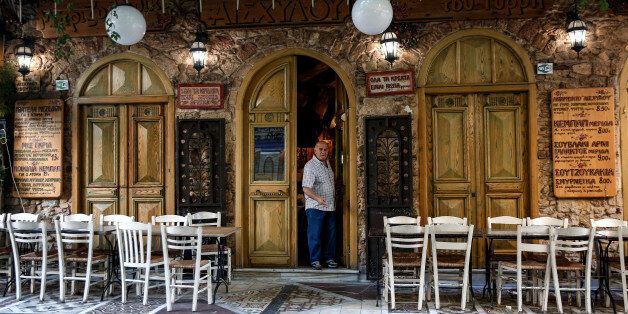 A man exits a tavern as empty tables stand outside in the Psyri neighborhood of Athens, Greece, on Friday, July 17, 2015. Germany's Parliament is set to ratify bridge financing and the start of talks for a three-year rescue plan. Photographer: Yorgos Karahalis/Bloomberg via Getty Images