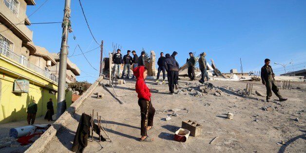 SULAYMANIYAH, IRAQ - NOVEMBER 13: People stand on a collapsed house, after a 7.3 magnitude earthquake hit northern Iraq, in Derbendihan district of Sulaymaniyah, Iraq on November 13, 2017. An earthquake measuring 7.3 on the Richter scale rocked northern Iraq and Iran, the U.S. Geological Survey said on Sunday evening. At least 61 people were killed and more than 300 others injured in Iran's border areas, according to information provided by the concerned authorities, said Iran's semi-official Fars News Agency. (Photo by Yunus Keles/Anadolu Agency/Getty Images)