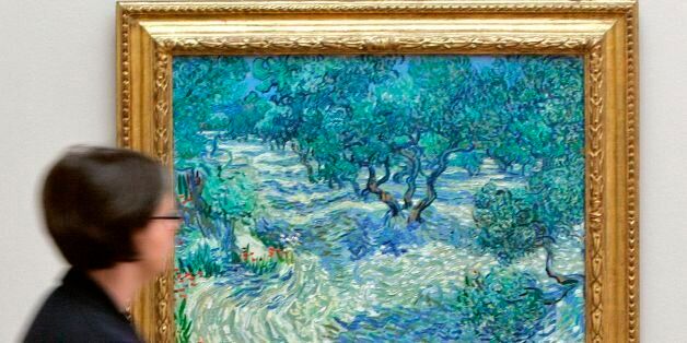 (FILES) File image taken April 23, 2009 shows a visitor looking at the painting 'Olive Trees' (Saint-Remy, June/July 1889) by Dutch artist Vincent van Gogh at the Kunstmuseum in Basel, Switzerland. It was revealed by a Kansas City art museum on November 7, 2017 that when conservators at The Nelson-Atkins Museum of Art put this Vincent van Gogh painting under the microscope, they found an unlikely intruder: a grasshopper trapped in the canvas's painterly whirls for 128 years. Mary Schafer, a conservator at The Nelson-Atkins Museum of Art, came across the tiny dried, brown carcass in the lower foreground while studying the painting of olive groves. The find reflects the artist's practice of painting in the outdoors, where it was often windy enough to send dust, grass and insects flying. / AFP PHOTO / NICHOLAS RATZENBOECK / TO GO WITH AFP STORY by Olivia Hampton 'There is a dead bug in the Van Gogh.' (Photo credit should read NICHOLAS RATZENBOECK/AFP/Getty Images)