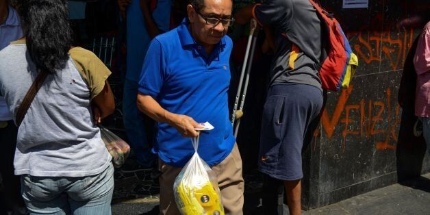 A man holds two bags of flour after queuing outside a supermarket in Caracas to buy basic foodstuffs and household products on November 10, 2017.In crisis-stricken Venezuela, the cost of the basic basket of goods soared to nearly 2.7 million bolivars in September, the equivalent of six minimum monthly wages. / AFP PHOTO / FEDERICO PARRA (Photo credit should read FEDERICO PARRA/AFP/Getty Images)