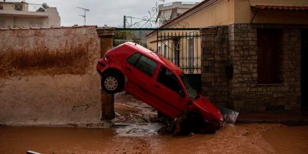 A damaged car is stuck at the entrance of a house, in a flooded street of Mandra, northwest of Athens, on November 15, 2017, after heavy overnight rainfall. At least 14 people died on November 15, 2017 after a freak overnight downpour with the force of a 'waterfall' flooded three towns in Greece, officials said. The flooding, described as the worst in 20 years, struck the towns of Mandra, Nea Peramos and Megara, a semi-rural area west of Athens where many factories and warehouses are based. / AFP PHOTO / Angelos Tzortzinis (Photo credit should read ANGELOS TZORTZINIS/AFP/Getty Images)