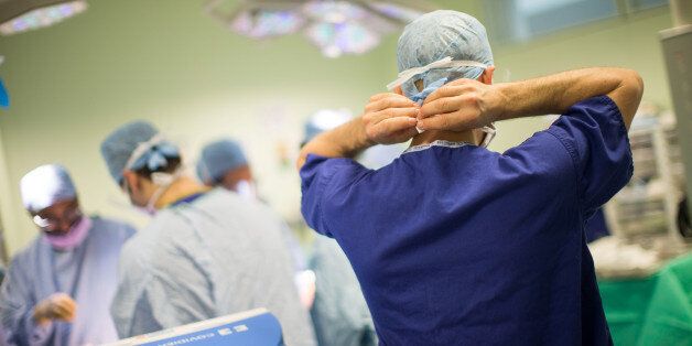 FILE: A member of the medical staff secures his face mask whilst working inside an operating theater at Queen Elizabeth Hospital Birmingham, part of the University Hospitals Birmingham NHS Foundation Trust, in Birmingham, U.K., on Monday, Feb. 20, 2017. As the U.K. government proposes spending 160 million pounds ($207 million) to support medical research and health care we select our best archive images on health. Photographer: Matthew Lloyd/Bloomberg via Getty Images