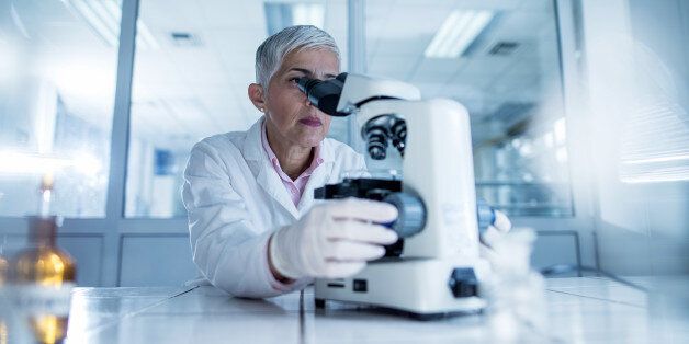 Female scientist looking through a microscope while working in a laboratory.