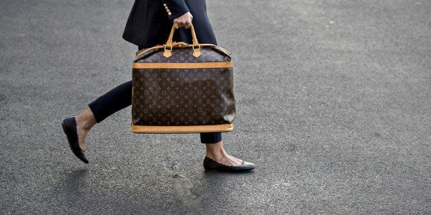 An aide carries a Louis Vuitton handbag to Marine One on the South Lawn of the White House before U.S. President Donald Trump and U.S. First Lady Melania Trump, not pictured, board in Washington, D.C., U.S., on Friday, Nov. 3, 2017. Trump said this morning he doesn't remember much about a March 2016 meeting in which a campaign foreign policy adviser raised the idea of seeking meetings with Russian officials and then continued contacts with Russian intermediaries. Photographer: Andrew Harrer/Bloomberg via Getty Images