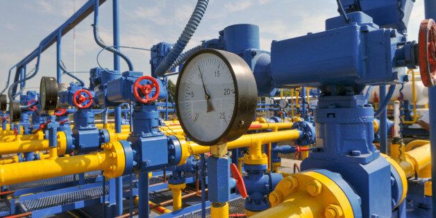 Pressure meter and red faucet with steel yellow pipe in natural gas treatment plant in bright sunny summer day