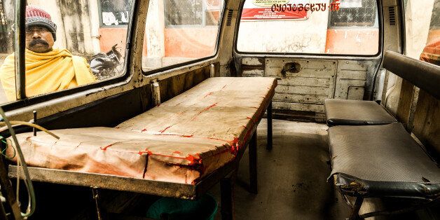 Bhadrapur, Nepal - January 18, 2014: A hospital visitor in eastern Nepal looks through a dilapidated ambulance parked in the compound.