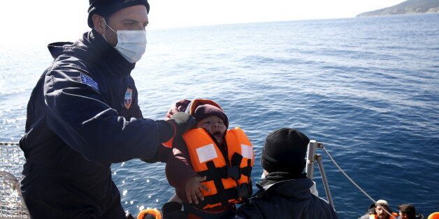 Greek Coast Guard officers move a baby from a dinghy carrying refugees and migrants aboard the Ayios Efstratios Coast Guard vessel, during a rescue operation at open sea between the Turkish coast and the Greek island of Lesbos, February 8, 2016. REUTERS/Giorgos Moutafis