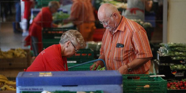 BERLIN, GERMANY - AUGUST 24: A volunteer guides Wolfgang, who said he is a retired construction engineer who fell on hard times after a business venture went sour, to choose groceries at a food distribution point organized by the Berliner Tafel at the Protestant Church Community Center Lichtenrade on August 24, 2017 in Berlin, Germany. Approximately 300 households rely on the weekly opportunity to pay a symbolic amount for expired groceries donated by local supermarkets and bakeries. Among the needy are Germans, especially pensioners whose pensions are insufficient, as well as migrants, including refugees who arrived since 2015 but also ethnic Germans from the former Soviet Union who came to Germany after 1989. Germany faces federal elections on September 24 and poverty, which has remained stubbornly persistent despite the country's strong economy, is a major election topic. (Photo by Sean Gallup/Getty Images)