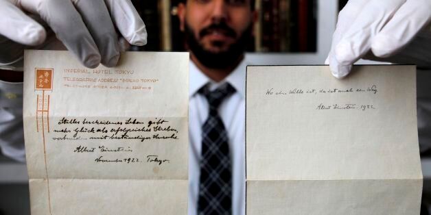 A picture taken on October 19, 2017, shows Gal Wiener, owner and manager of the Winner's auction house in Jerusalem, displays two notes written by Albert Einstein, in 1922, on hotel stationary from the Imperial Hotel in Tokyo Japan. A note that Albert Einstein gave to a courier in Tokyo, briefly describing his theory on happy living, has surfaced after 95 years and is up for auction in Jerusalem. / AFP PHOTO / MENAHEM KAHANA (Photo credit should read MENAHEM KAHANA/AFP/Getty Images)