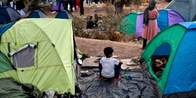 Recently arrived refugees sit in a makeshift tent camp near the overcrowded hotspot on the Greek eastern Aegean islands of Samos on October 13, 2017.More than 3,000 people on Samos are crammed into facilities designed to hold 700. Some 200 people, including families with children, are sleeping in tents in the woods due to a lack of space in the camp. Nearly 5,000 refugees, mostly Syrian or Iraqi families, crossed from Turkey to Greece in September - a quarter of all arrivals this year, UNHCR data shows. / AFP PHOTO / LOUISA GOULIAMAKI (Photo credit should read LOUISA GOULIAMAKI/AFP/Getty Images)