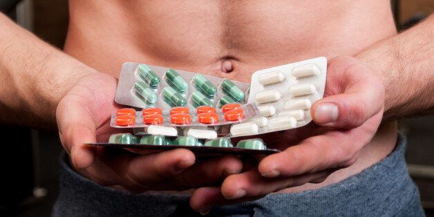 Muscle man holding bunch of blisters with colored vitamin pills