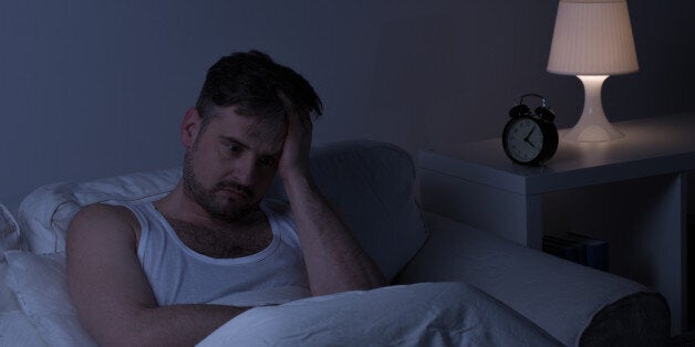 Man suffering from sleeplessness sitting in the bed