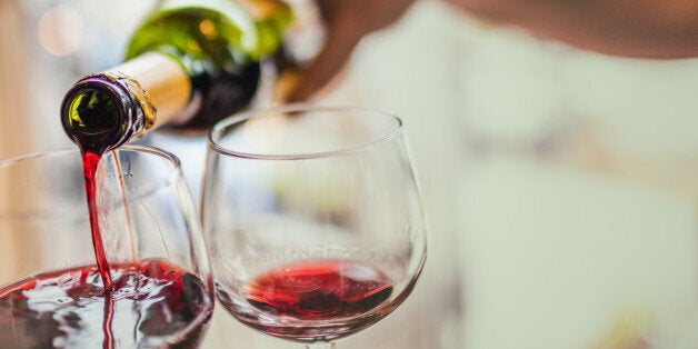 Unrecognizable man pouring red wine in two glasses.