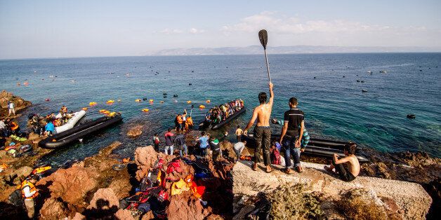 Syrian refugees arrive on a beach covered with life vests and dinghies on the Greek island of Lesbos.