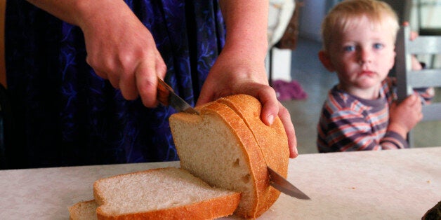 A woman from a Mennonite community slices bread for breakfast as her son looks on at their home in Cuauhtemoc November 9, 2012. More than a century after Mennonite farmers left Russia for North America in search of new lands and religious freedom, hundreds of their descendants in Mexico are thinking about completing the circle. Shortage of farmland, drought and conflict with rivals have made some Mennonites in northern Mexico wonder if the best way of providing for their families is to go back to the plains of eastern Europe their ancestors left in the 19th century. Picture taken November 9, 2012. To match Feature MEXICO-MENNONITES/ REUTERS/Jose Luis Gonzalez (MEXICO - Tags: FOOD SOCIETY RELIGION)