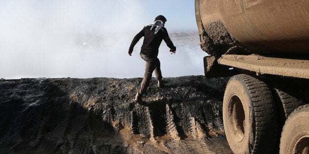 DEREK, SYRIA - NOVEMBER 14: A worker passes the steaming dregs of oil refined into diesel fuel on November 14, 2015 near Derek, in Rojava, Syria. The predominantly Kurdish autonomous Rojava region of northern Syria had previously been supplied with pretroleum from refineries in areas now under ISIL control, so Rojavans have begun crudely processing their own reserves into diesel for domestic fuel and heating needs. The Islamic State, however, continues to pump and export millions of barrels of