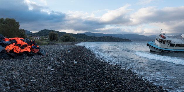Lesbos, Greece - October 25, 2015: The migrants have moved on, but on a beach in Molyvos, on the north coast of the Greek island of Lesbos, the remains of their journey across the sea from Turkey are visible. On the left is a mound containing life jackets as well as the rubber remains of inflatable boats. On the right is a beached ship that earlier in the month had carried one group of migrants to the island.