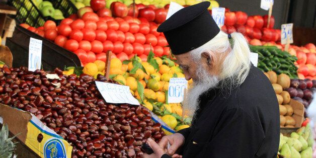 A Greek orthodox priest searches for change to buy vegetables in Athens November 8, 2011. Greek party leaders were struggling on Tuesday to agree on a new prime minister, under pressure from the European Union to push through a bailout to save the country's finances and end the chaos threatening the euro. REUTERS/Panayiotis Tzamaros (GREECE - Tags: POLITICS BUSINESS)