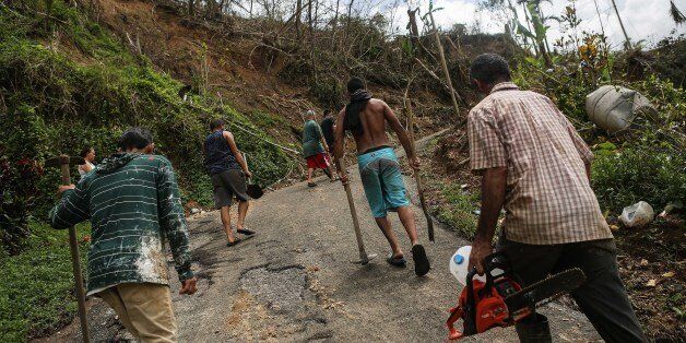 PELLEJAS, PUERTO RICO - OCTOBER 10: Community members walk up to their houses after working to clear the street of debris nearly three weeks after Hurricane Maria hit the island, on October 10, 2017 in Pellejas, Adjuntas municipality, Puerto Rico. The men said they have received virtually no govenmental assistance and their houses have no electricity or running water. Only 16 percent of Puerto Rico's grid electricity has been restored. Puerto Rico experienced widespread damage including most of the electrical, gas and water grid as well as agriculture after Hurricane Maria, a category 4 hurricane, swept through. (Photo by Mario Tama/Getty Images)