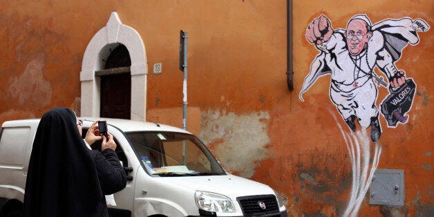 A nun takes a picture of a large drawing of Pope Francis depicting him as a superhero on a wall near the Vatican January 29, 2014. The Argentinian Pope is shown taking off into air with his right fist clenched in a classic Superman style. REUTERS/Alessandro Bianchi (ITALY - Tags: RELIGION SOCIETY)