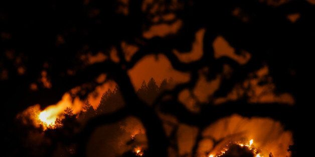 KENWOOD, CA - OCTOBER 16: The Nuns Fire is seen on a hillside through the branches of a tree on Oct. 16, 2017 in Kenwood, California. At least 40 people are confirmed dead, dozens are still missing, and at least 5,700 buildings have been destroyed since wildfires broke out a week ago. (Photo by Elijah Nouvelage/Getty Images)