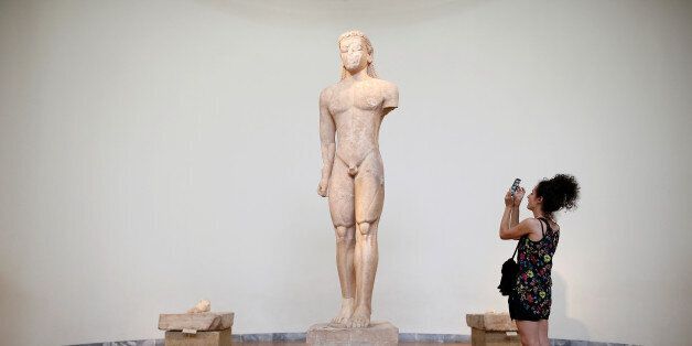 A tourist takes a picture of an ancient Naxian marble kouros statue at the National Archaeological Museum in Athens, Greece, August 3, 2017. REUTERS/Alkis Konstantinidis