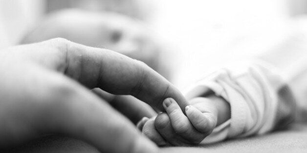 right after birth, baby is holding father's finger