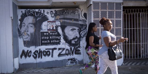 Women walk past a sign with a message to end gun violence in the Sandtown neighborhood of west Baltimore on August 8, 2017.Baltimore, a city of 2.8 million, is troubled by drug use, poverty and racial segregation problems. In 2016 violent crime in Baltimore was up 22 percent and murders up 78 percent, according to Attorney General Jeff Sessions. / AFP PHOTO / MANDEL NGAN (Photo credit should read MANDEL NGAN/AFP/Getty Images)