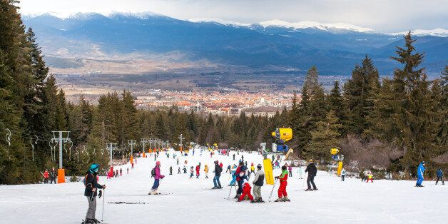 Bansko, Bulgaria - February 11, 2016: Skiers on the slope , ski lift, mountains view and Bansko town panorama