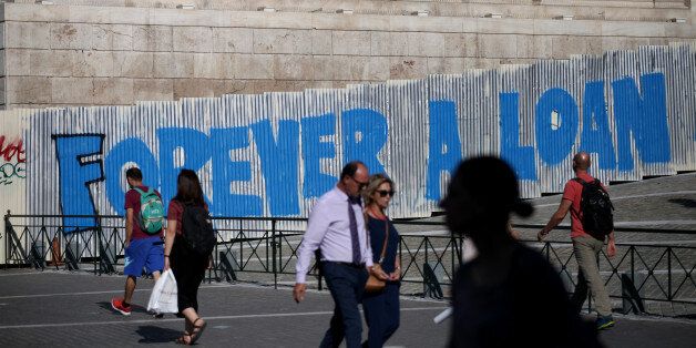 People walk by a graffiti that reads Forever a Loan in Athens city center, Greece, September 7, 2017. (Photo by Giorgos Georgiou/NurPhoto via Getty Images)