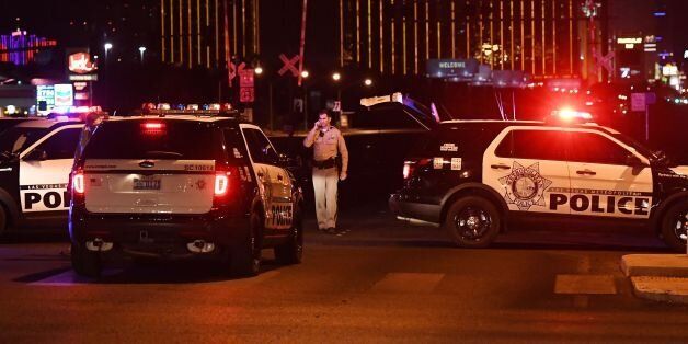Police form a perimeter around the road leading to the Mandalay Hotel (background) after a gunman killed at least 50 people and wounded more than 200 others when he opened fire on a country music concert in Las Vegas, Nevada on October 2, 2017. Police said the gunman, a 64-year-old local resident named as Stephen Paddock, had been killed after a SWAT team responded to reports of multiple gunfire from the 32nd floor of the Mandalay Bay, a hotel-casino next to the concert venue. / AFP PHOTO / Mark RALSTON (Photo credit should read MARK RALSTON/AFP/Getty Images)