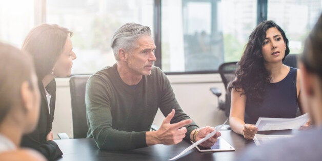 Mature businessman talking to his colleagues on a meeting at the office.