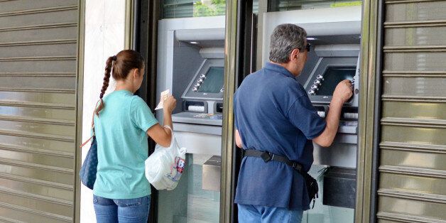 Athens, Greece - June 30th, 2015: customers waiting to use an automated teller machine (ATM), outside a Greek Bank