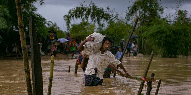 COX'S BAZAR, BANGLADESH - SEPTEMBER 19: Refugees cross a flooded bridge in the Balukhali Rohingya refugee camp on September 19, 2017 in Cox's Bazar, Bangladesh. Over 400,000 Rohingya refugees have fled into Bangladesh since late August during the outbreak of violence in the Rakhine state as Myanmar's de facto leader Aung San Suu Kyi broke her silence on the Rohingya crisis on Tuesday and defended the security forces while criticism on her handling of the Rohingya crisis grows. Recent satellite images released by Amnesty International provided evidence that security forces were trying to push the minority Muslim group out of the country. (Photo by Allison Joyce/Getty Images)