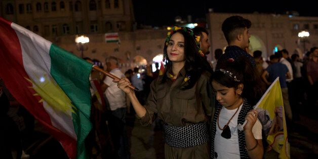 ERBIL, IRAQ - SEPTEMBER 25: A woman holds a Kurdish flag in the city centre on September 25, 2017 in Erbil, Iraq. Despite strong objections from neighboring countries and the Iraqi government, some five million Kurds took to the polls today across three provinces in a historic independence referendum. (Photo by Younes Mohammad/Getty Images)