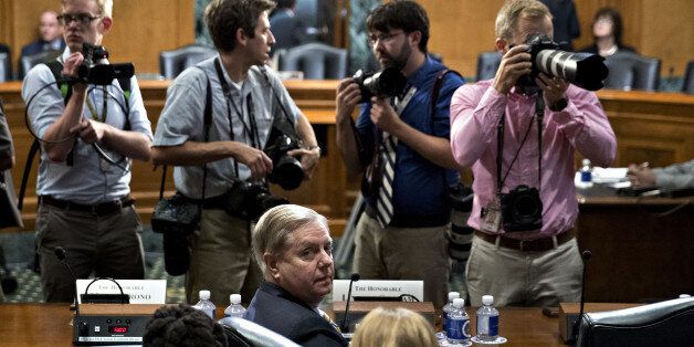 Senator Lindsey Graham, a Republican from South Carolina, bottom center, stays seated during a disruption in a Senate Finance Committee hearing to consider the Graham-Cassidy-Heller-Johnson proposal in Washington, D.C., U.S., on Monday, Sept. 25, 2017. Senators sponsoring a last-ditch Obamacare repeal bill raced to save it from near-certain death Sunday, circulating a new version aimed at winning over several GOP holdouts. Photographer: Andrew Harrer/Bloomberg via Getty Images