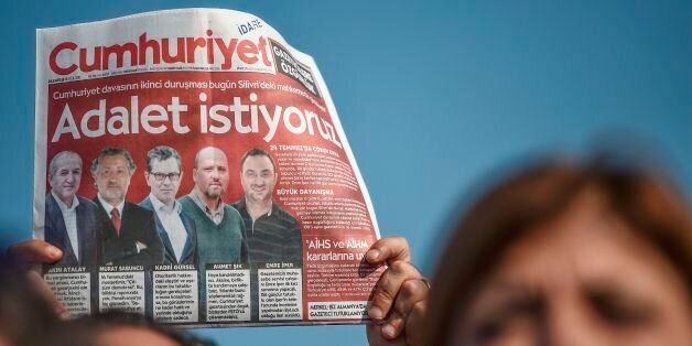 A protester holds Cumhuriyet daily newspaper during a demonstration before the controversial trial of staff from Turkey's main opposition daily on September 11, 2017 in the Silivri district in Istanbul. The case, which opened in Istanbul in July, involves 17 current and former writers, cartoonists and executives from Cumhuriyet ('Republic') who are being tried on 'terror' charges in a move denounced by supporters as absurd. / AFP PHOTO / OZAN KOSE (Photo credit should read OZAN KOSE/AFP/Getty Images)
