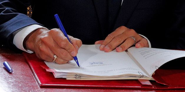 French President Emmanuel Macron signs documents in front of the media to promulgate a new labour bill in his office at the Elysee Palace in Paris, on September 22, 2017.Macron on September 22 signed sweeping changes to France's complex labour code into law, sealing a signature reform after four months at the helm. The measures, which have triggered mass protests, are designed to give employers more flexibility to negotiate pay and conditions with their workers and makes it easier to lay off staff. / AFP PHOTO / POOL / PHILIPPE WOJAZER (Photo credit should read PHILIPPE WOJAZER/AFP/Getty Images)