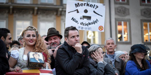 MUNICH, GERMANY - SEPTEMBER 22: A Iranian Woman in traditional bavarian dress with a purse showing Angela Merkel's portrait stands in front of protesters at Chancellor Angela Merkel's (CDU) last big election campaign rally before German federal elections on September 22, 2017 in Munich, Germany. Germans will go to the polls this coming Sunday and Merkel currently has a double-digit lead over her arrivals, though the final election outcome remains uncertain as a significant percentage of voters have so far remained undecided. (Photo by Philipp Guelland/Getty Images)