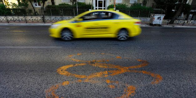 A taxi drives by fading Olympic rings which mark the Olympic Traffic Lane on an avenue leading to the Athens 2004 Olympic Complex in Athens July 26, 2014. Ten years after Greece hosted the world's greatest sporting extravaganza, many of its once-gleaming Olympic venues have been abandoned while others are used occasionally for non-sporting events such as conferences and weddings. For many Greeks who swelled with pride at the time, the Olympics are now a source of anger as the country struggles through a six-year depression, record unemployment, homelessness and poverty. Just days before the anniversary of the Aug. 13-29 Games in 2004, many question how Greece, among the smallest countries to ever host the Games, has benefited from the multi-billion dollar event. Picture taken July 26, 2014. REUTERS/Yannis Behrakis (GREECE - Tags: BUSINESS POLITICS SPORT TRANSPORT)ATTENTION EDITORS: PICTURE 25 OF 33 FOR WIDER IMAGE PACKAGE 'TEN YEARS ON - ATHENS' FADING OLYMPIC STADIUMS' TO FIND ALL IMAGES SEARCH 'BEHRAKIS KARAHALIS'