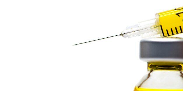 Syringe with yellow fluid on a white background