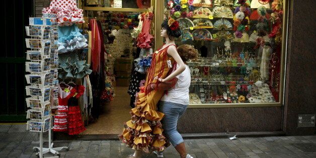 A worker carries a mannequin in a typical Sevillana dress to place it inside a clothing store in downtown Malaga, southern Spain, July 23, 2015. Spain's jobless rate dropped to its lowest level in over three years in the second quarter, offering a boost to Rajoy as he seeks to persuade voters that an economic recovery is taking root. At 22.4 percent, the unemployment rate is still higher than anywhere else in Europe bar crisis-hit Greece and has not dipped below a fifth of the workforce in five years, even after Spain exited recession in mid-2013. REUTERS/Jon Nazca