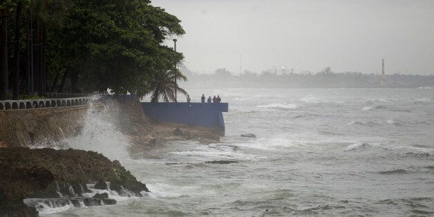 People stand by the sea in the rain in the La Cienaga neighborhood on September 7, 2017, as Hurricane Irma approaches. Irma was packing maximum sustained winds of up to 185 mph (295 kph) as it followed a projected path that would see it hit the northern edges of the Dominican Republic and Haiti on Thursday, continuing past eastern Cuba before veering north for Florida. / AFP PHOTO / Erika SANTELICES (Photo credit should read ERIKA SANTELICES/AFP/Getty Images)