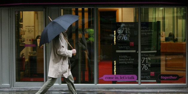 FILE: A pedestrian holds an umbrella as he shelters from the rain whilst walking past a branch of the Northern Rock Plc bank in London, U.K., on Friday, Jan. 11, 2008. This week marks the 10-year anniversary of the Northern Rock Plc failure that for shadowed the 2008 financial crisis. Queues formed outside branches as thousands of Northern Rock customers led the first run on a British bank since 1866. As we look back on the anniversary, our editors select the best archive images from the crisis.
