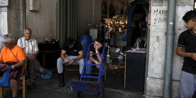 Youths (C) working at Athens' main fish market rest at the entrance of the market June 30, 2015. The head of the European Commission made a last-minute offer to try to persuade Greek Prime Minister Alexis Tsipras to accept a bailout deal he has rejected before a referendum on Sunday which EU partners say will be a choice of whether to stay in the euro. REUTERS/Alkis Konstantinidis