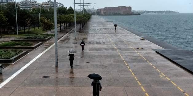 People walk with umbrellas under a rainfall on the waterfront of Thessaloniki on July 17, 2017. Greeks are bearing the brunt of a weather phenomenon called Medusa with heavy rains, hailstorms, and strong winds. / AFP PHOTO / SAKIS MITROLIDIS (Photo credit should read SAKIS MITROLIDIS/AFP/Getty Images)