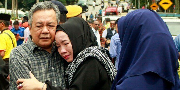 Nik Azlan Nik Abdul Kadir (L), father of one of the victims comforts his wife outside the Darul Quran Ittifaqiyah religious school in Kuala Lumpur on September 14, 2017.Twenty-four people, mostly teenage boys, were killed on September 14 when a blaze tore through a Malaysian religious school, in what officials said was one of the country's worst fire disasters for years. / AFP PHOTO / SADIQ ASYRAF (Photo credit should read SADIQ ASYRAF/AFP/Getty Images)